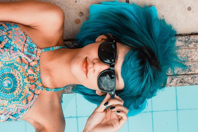 mulher com óculos de sol e cabelo azul